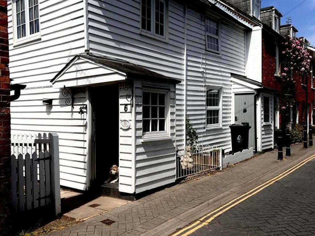 a white house with a dog sitting in the doorway at Bridewell Cottage in the heart of Tenterden - Pass The Keys in Tenterden