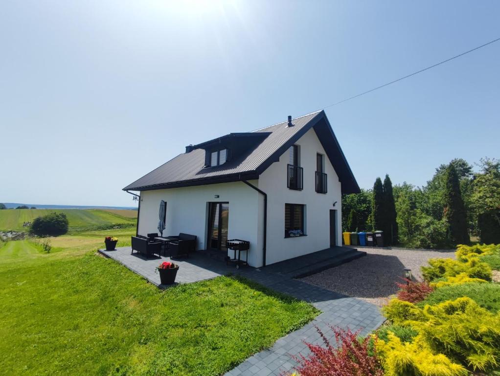 una pequeña casa blanca con techo negro en Agroturystyka Zdolina, en Krajno Pierwsze
