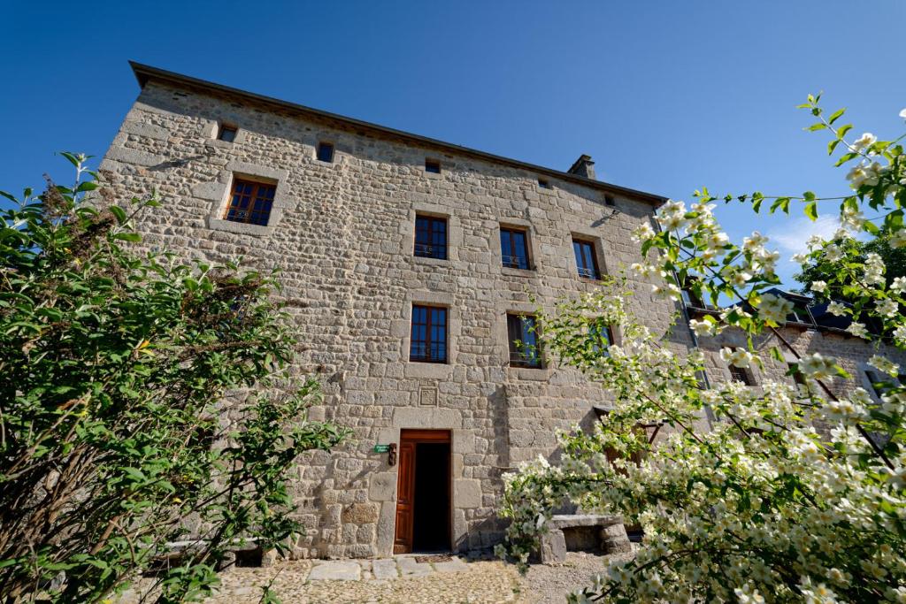 een oud stenen gebouw met een deur en bomen bij Le petit château du Villard 
