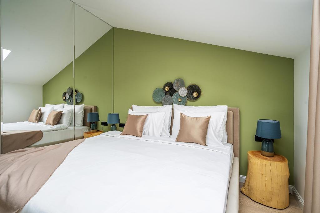 a bedroom with a large white bed and a green wall at Blanche Cliff Apartments in Sveti Stefan
