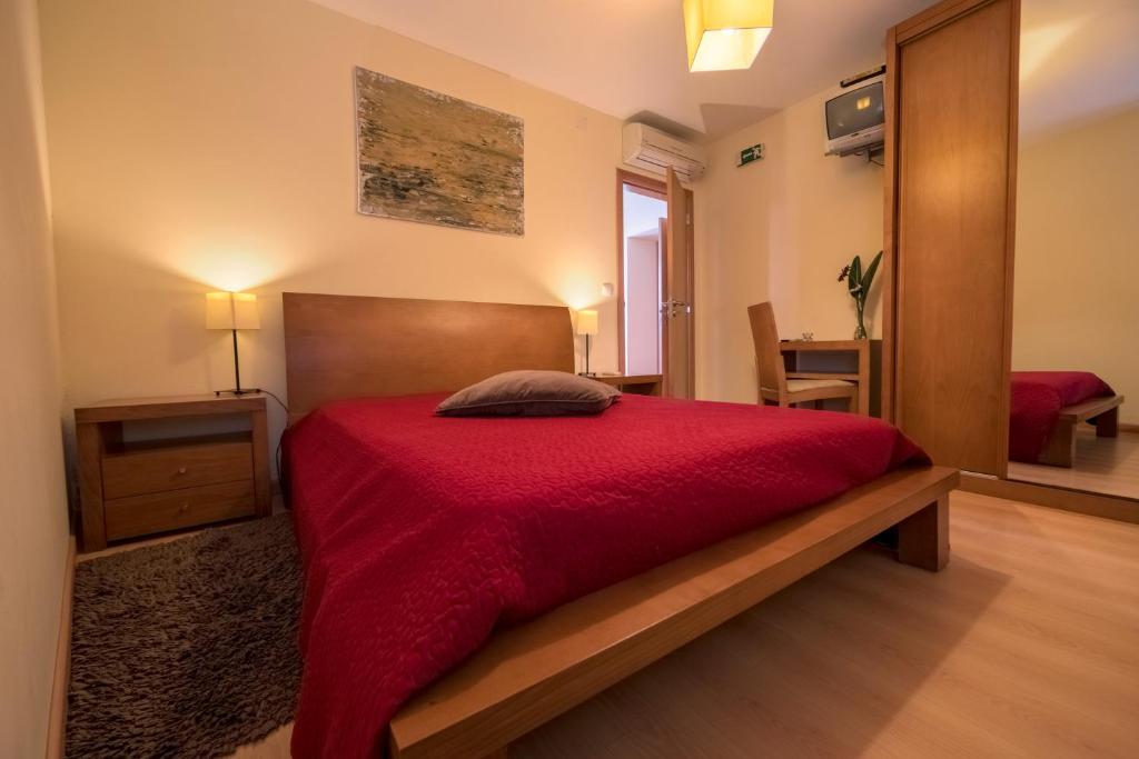um quarto com uma cama com uma colcha vermelha em A Velha Casa em Vila de Rei