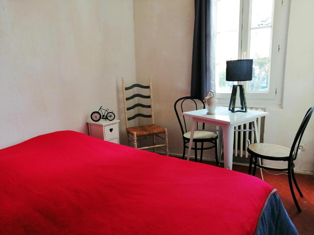 - une chambre avec un lit rouge, une table et des chaises dans l'établissement Appartement charmant à La Seyne-sur-Mer 44 m² avec terrasse, à La Seyne-sur-Mer