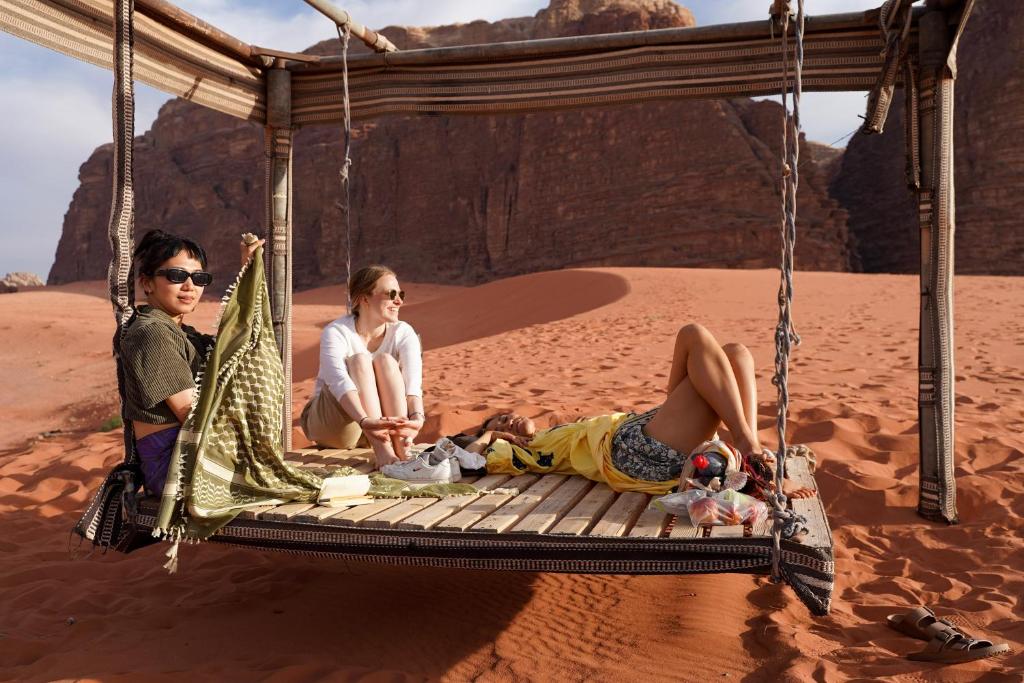 two women sitting on a swing in the desert at Walid Bedouin Camp in Wadi Rum
