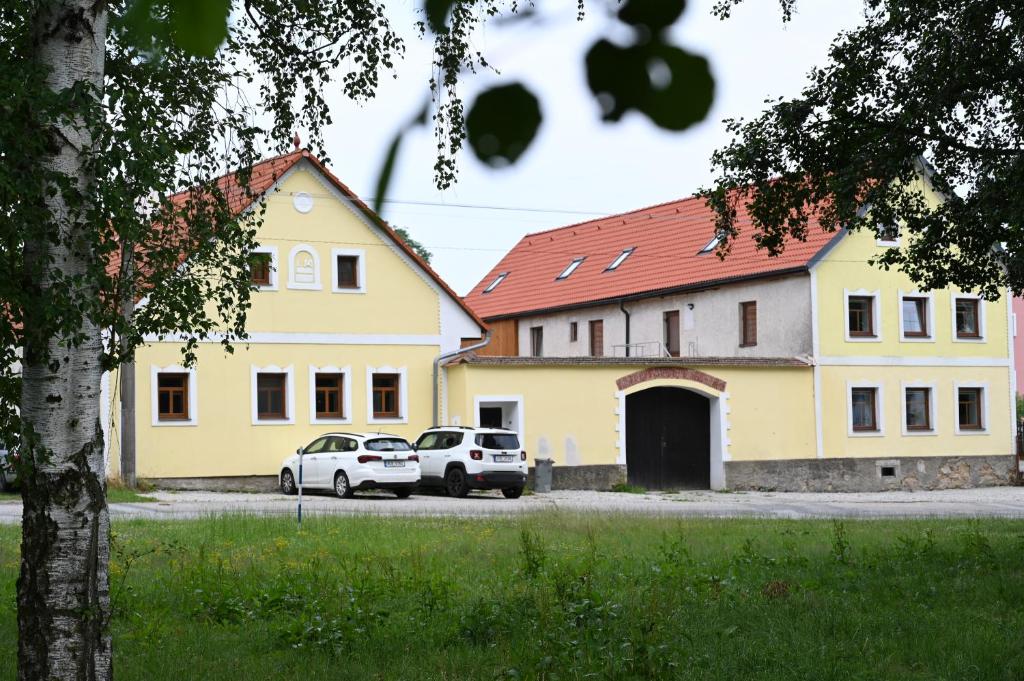 Penzion Mezi řádky في جينديتشوف هراديك: سيارتين متوقفتين امام مبنى اصفر