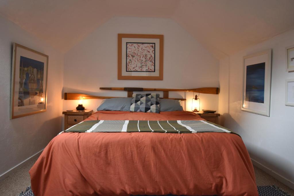 a bedroom with a large orange bed in a room at Yewtree Cottage - 'The Art House' and Garden in Hunters Quay