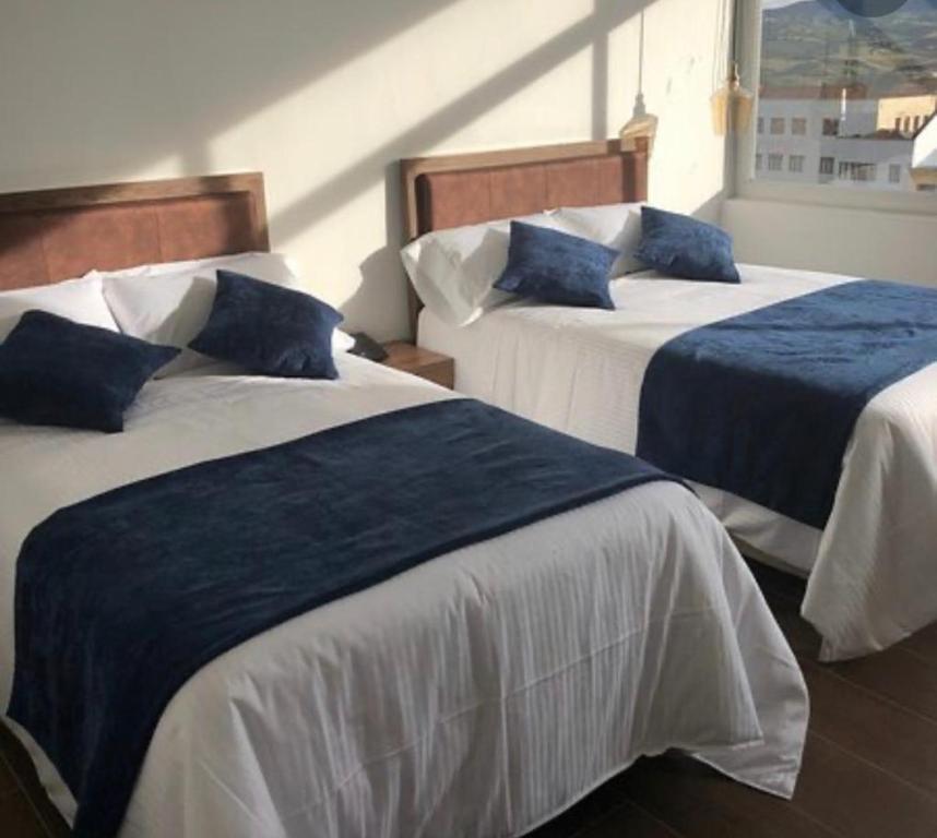 a bedroom with two beds with blue and white sheets at Hotel Amiraty in Ipiales