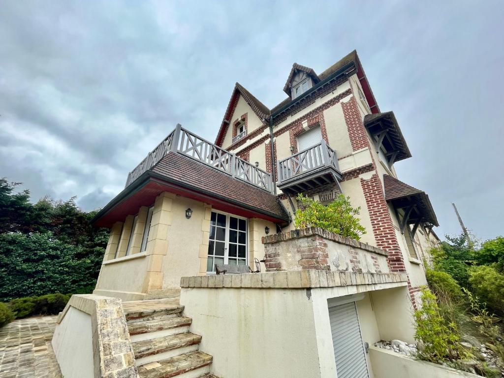 an old house with a balcony on top of it at Villa au bord de la mer à Benerville in Bénerville-sur-Mer