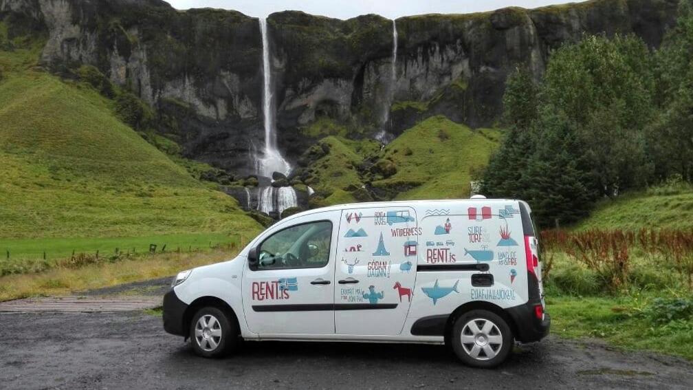 un furgone bianco parcheggiato di fronte a una cascata di Rent Campervans a Keflavík