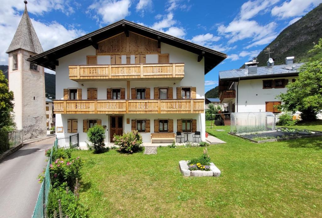 La Gerla Casa Vacanze Dolomiti في Perarolo di Cadore: منزل كبير أمامه ساحة خضراء