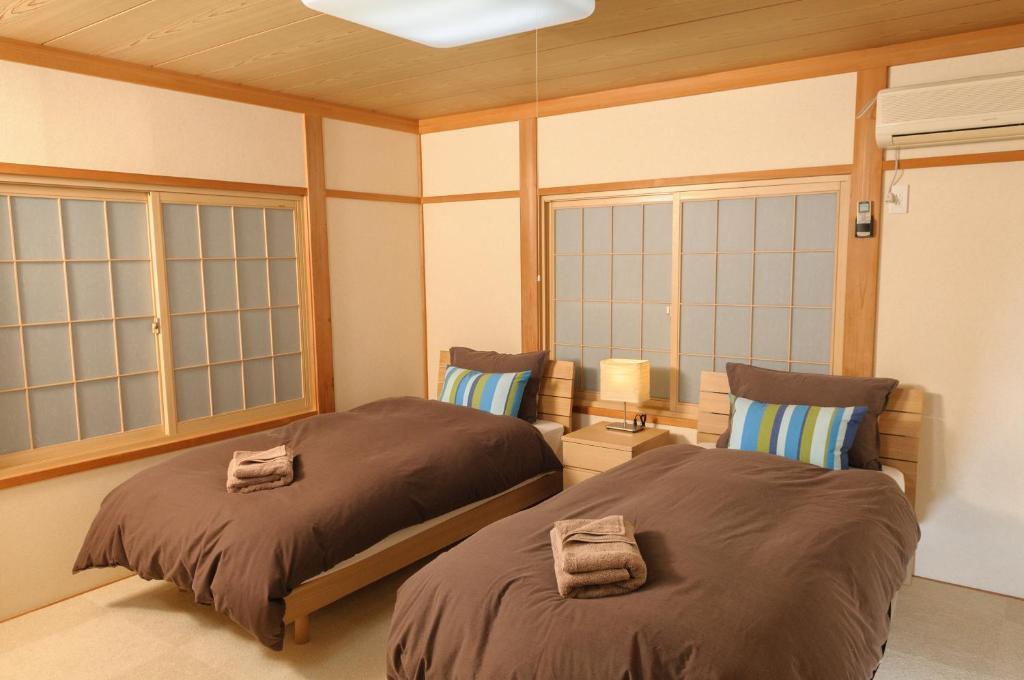 two beds in a room with windows at Le Bocage - Hakuba Echoland Chalets in Hakuba
