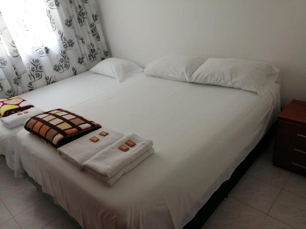 a large white bed with towels on top of it at Hostal Dante in San Gil