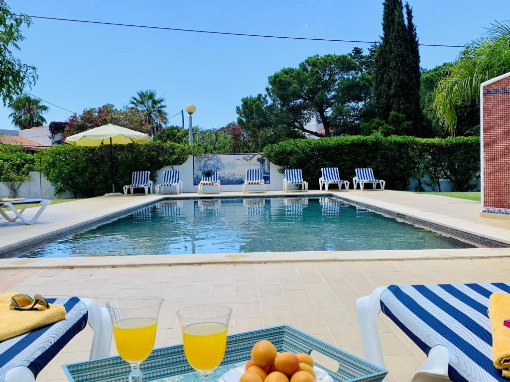 a table with two glasses of orange juice and some fruit on it at 3 bedrooms house at Carvoeiro 650 m away from the beach with shared pool furnished garden and wifi in Carvoeiro