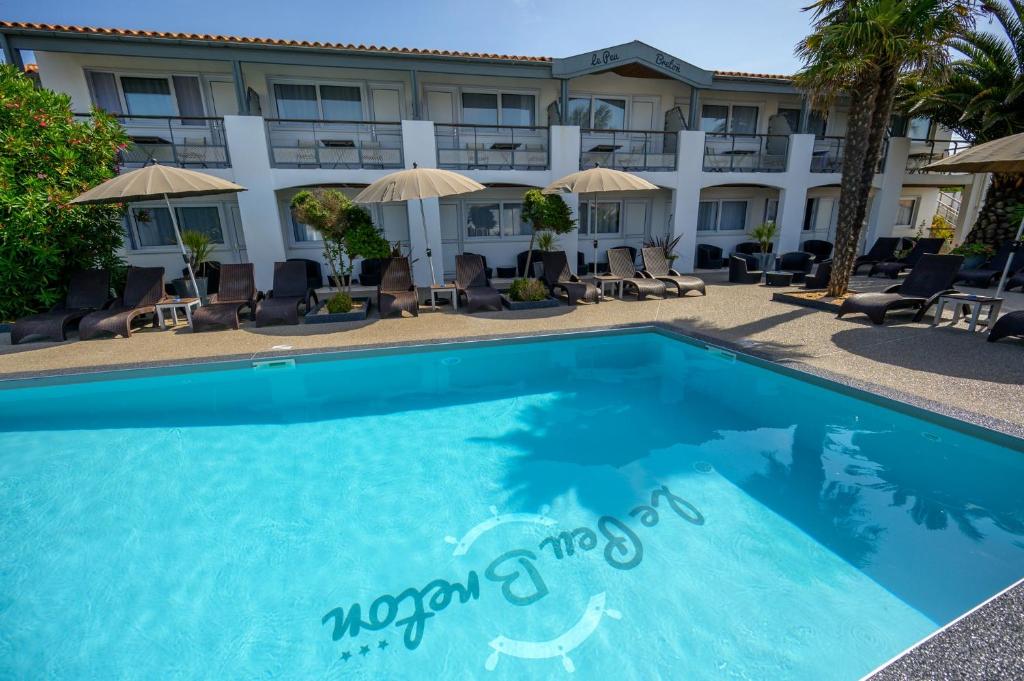 a swimming pool in front of a hotel at Hôtel Le Peu Breton in Sainte-Marie-de-Ré