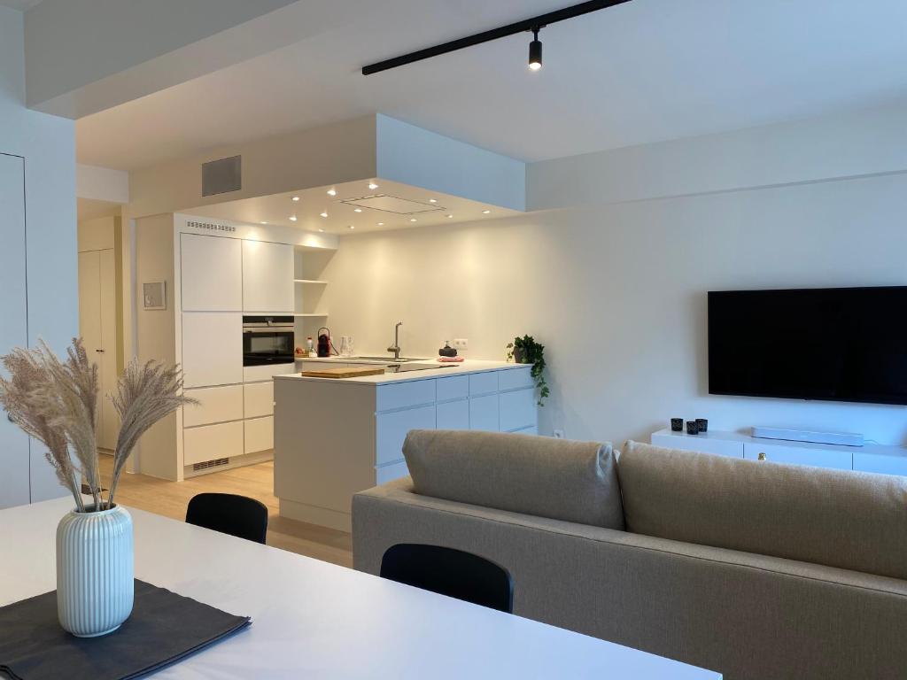 een woonkamer en een keuken met een bank en een tafel bij DE HORLOGE luxueus vakantie appartement in Oostende