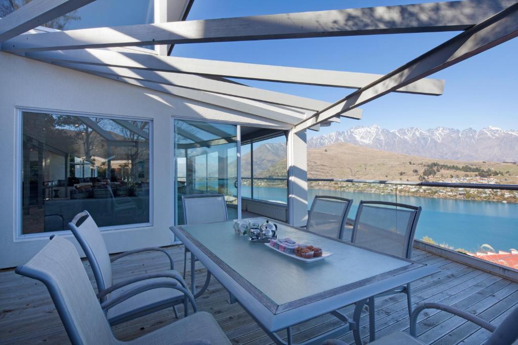 a table and chairs on a deck with a view of the water at Star Lane by Amazing Accom in Queenstown