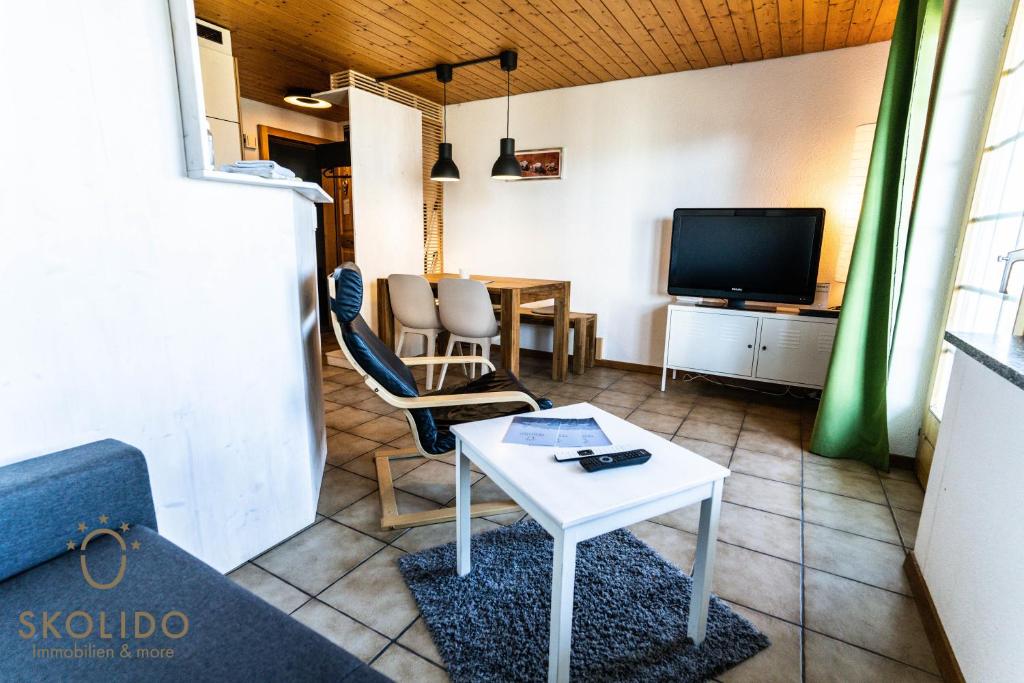a living room with a table and a tv at 2-Zimmerwohnung an zentraler Lage/Ski-in, Ski-out in Riederalp