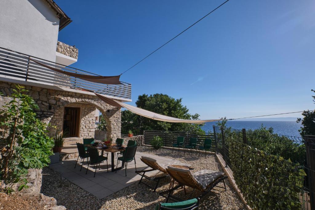 une terrasse avec une table et des chaises et l'océan dans l'établissement Kuća za odmor Baya, à Stara Baška