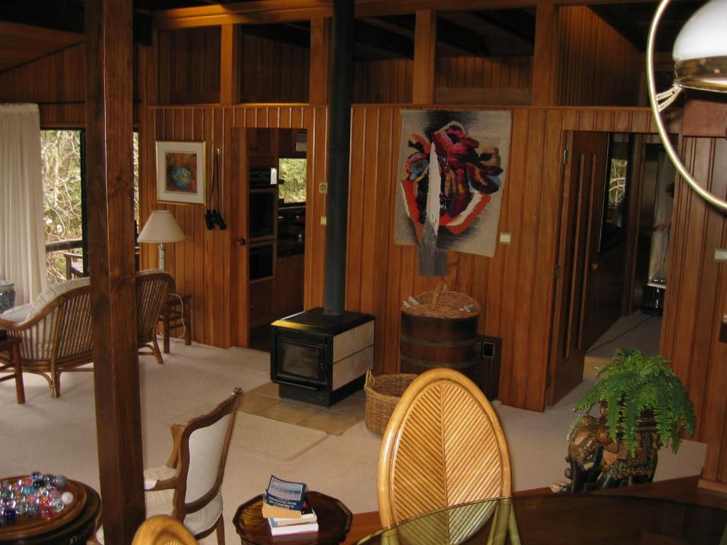 a living room with wood paneling and a stove at Rapaura Watergardens in Tapu
