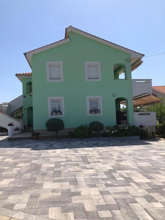 a blue house with a stone courtyard in front of it at Lucija Apartments in Krk