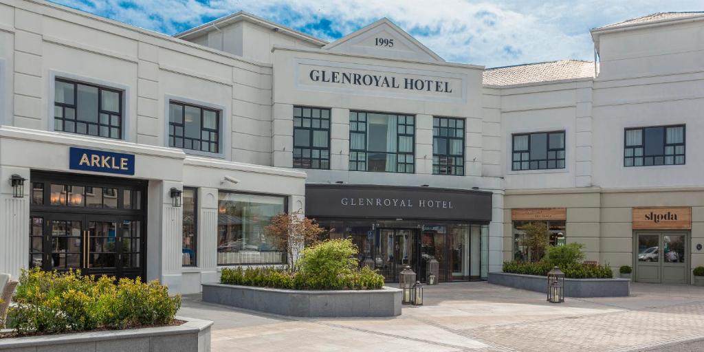 a large white building with a group of shops at Glenroyal Hotel in Maynooth