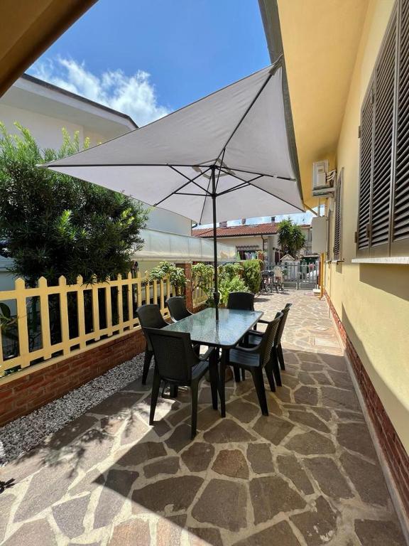 stół i krzesła z parasolem na patio w obiekcie villino Morena w mieście Torre del Lago Puccini