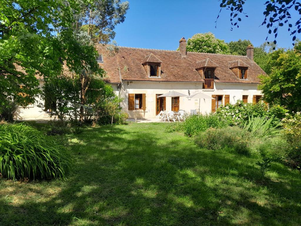 ein großes weißes Haus mit einem Rasenhof in der Unterkunft Ravissante longère avec grand jardin et cheminée in Pellevoisin