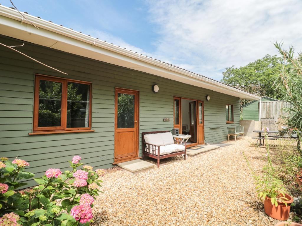 a green house with a bench and a porch at The Stables in Winscombe