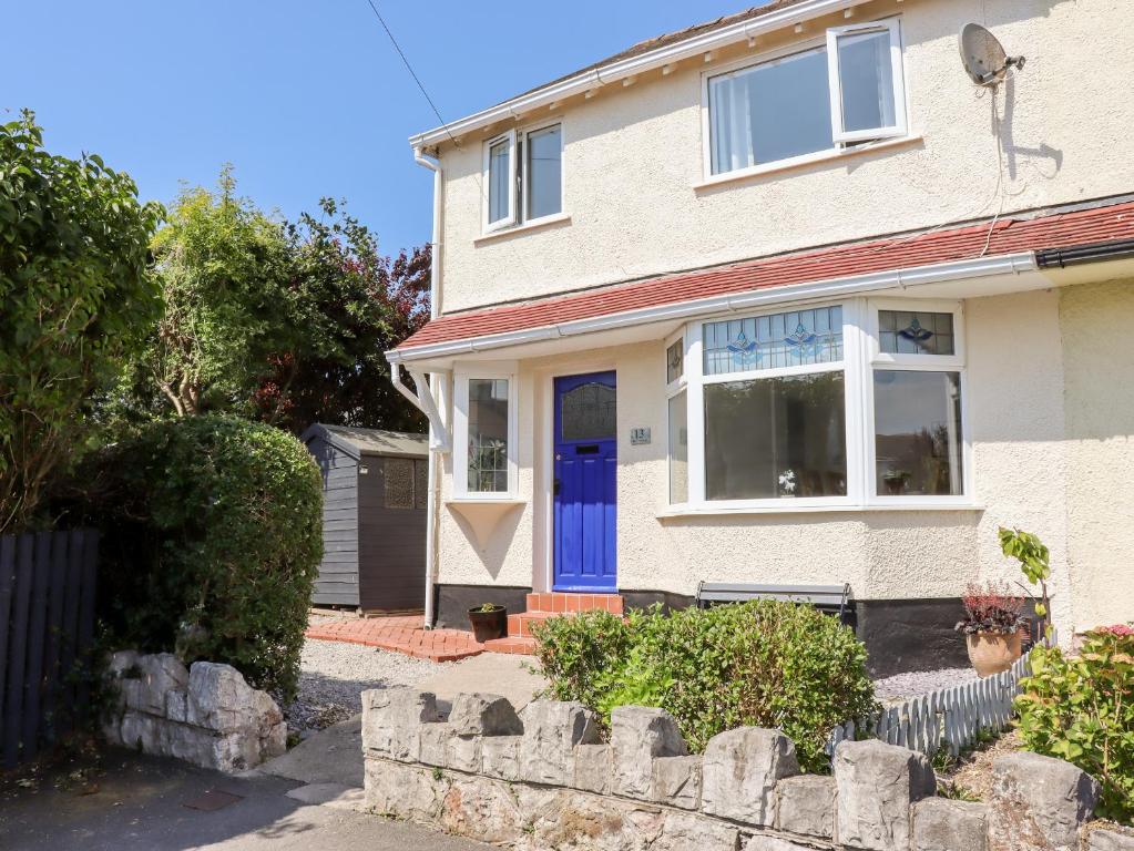 a white house with a blue door at 13 The Crescent in Llandrillo-yn-Rhôs