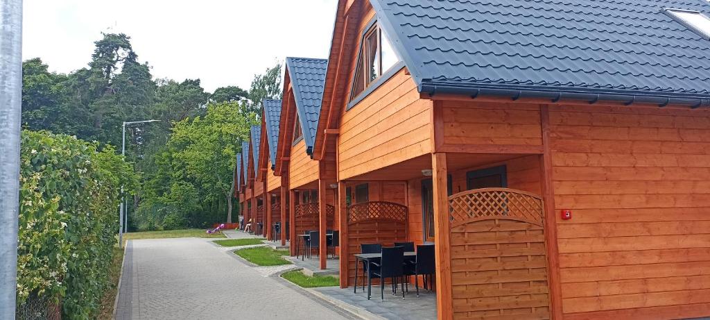 a wooden building with tables and chairs on a sidewalk at Domki North Side in Pustkowo