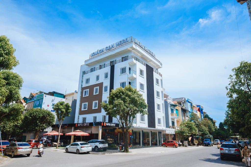 un grand bâtiment blanc dans une rue de la ville avec des voitures dans l'établissement Khách sạn Hero Thanh Hóa, à Thanh Hóa