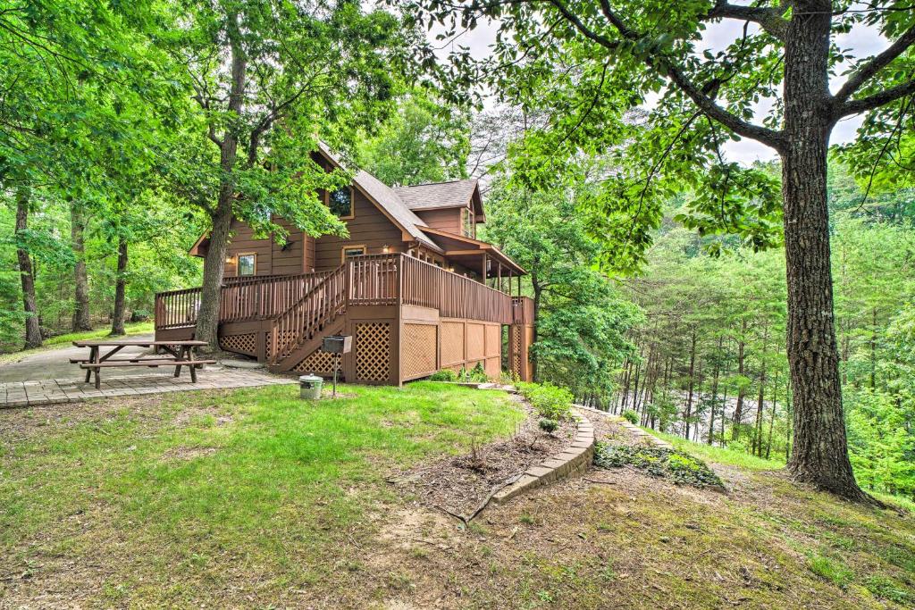 eine Hütte im Wald mit einem Picknicktisch und einem Baum in der Unterkunft Central Sevierville Cabin with Hot Tub and Views! in Sevierville