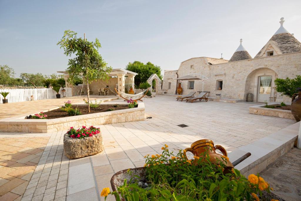 a courtyard with a stone building with flowers and plants at Trullo Arteanima in Locorotondo