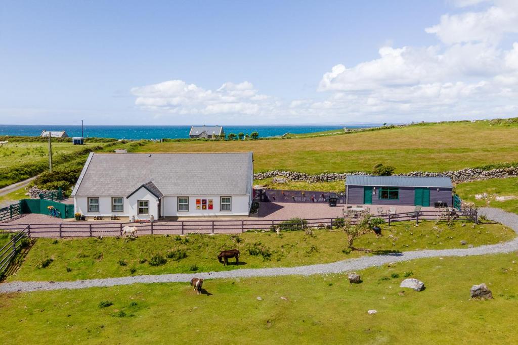 ein Haus auf einem Hügel mit dem Ozean im Hintergrund in der Unterkunft Into The Burren in Murroogh