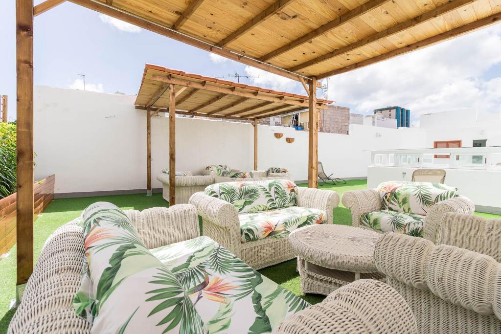 une terrasse avec des chaises en osier et une pergola dans l'établissement El Rincón de los Artistas, à Las Palmas de Gran Canaria