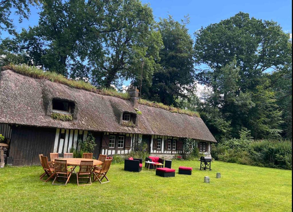 a house with a grass roof with a table and chairs at Chaleureuse chaumière proche Château et plages in Pleine-sève