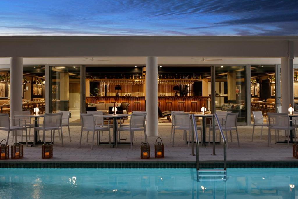 uma piscina em frente a um restaurante com mesas e cadeiras em The Kimpton Shorebreak Fort Lauderdale Beach Resort em Fort Lauderdale