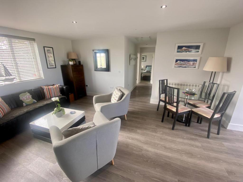 Una sala de estar con un sofá y sillas y una mesa. en 2 Bedroom cottage sleeps 4 with Hot-tub, & shared Pool use, en Sennen