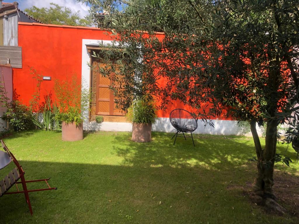 a garden with a red wall and a chair in a yard at CHAMBRES chez l'habitant Córdoba et Lhassa in Bordeaux