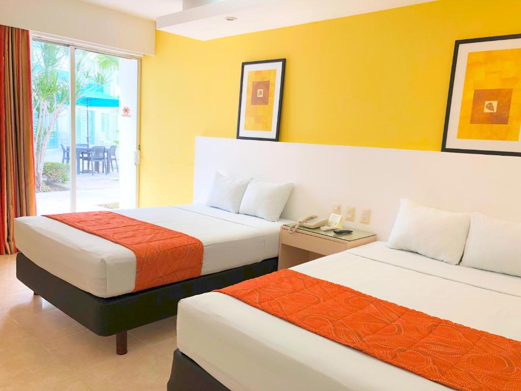 a hotel room with two beds and a window at Hotel Los Cocos Chetumal in Chetumal