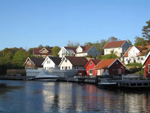 um grupo de casas ao lado de uma massa de água em Flekkerøy sjøboder 4 soverom 8 senger em Kjere