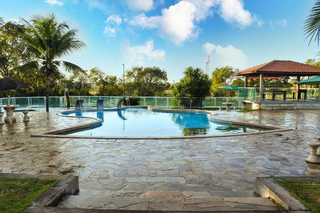 a swimming pool in a park with palm trees at Hotel Fazenda Haras in Olímpia