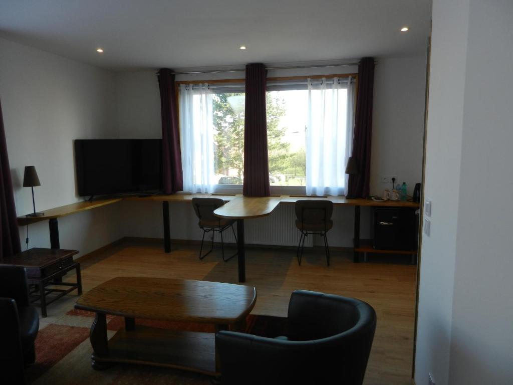 a living room with a table and chairs and a tv at Hôtel Les Charmilles de Mormal in Landrecies