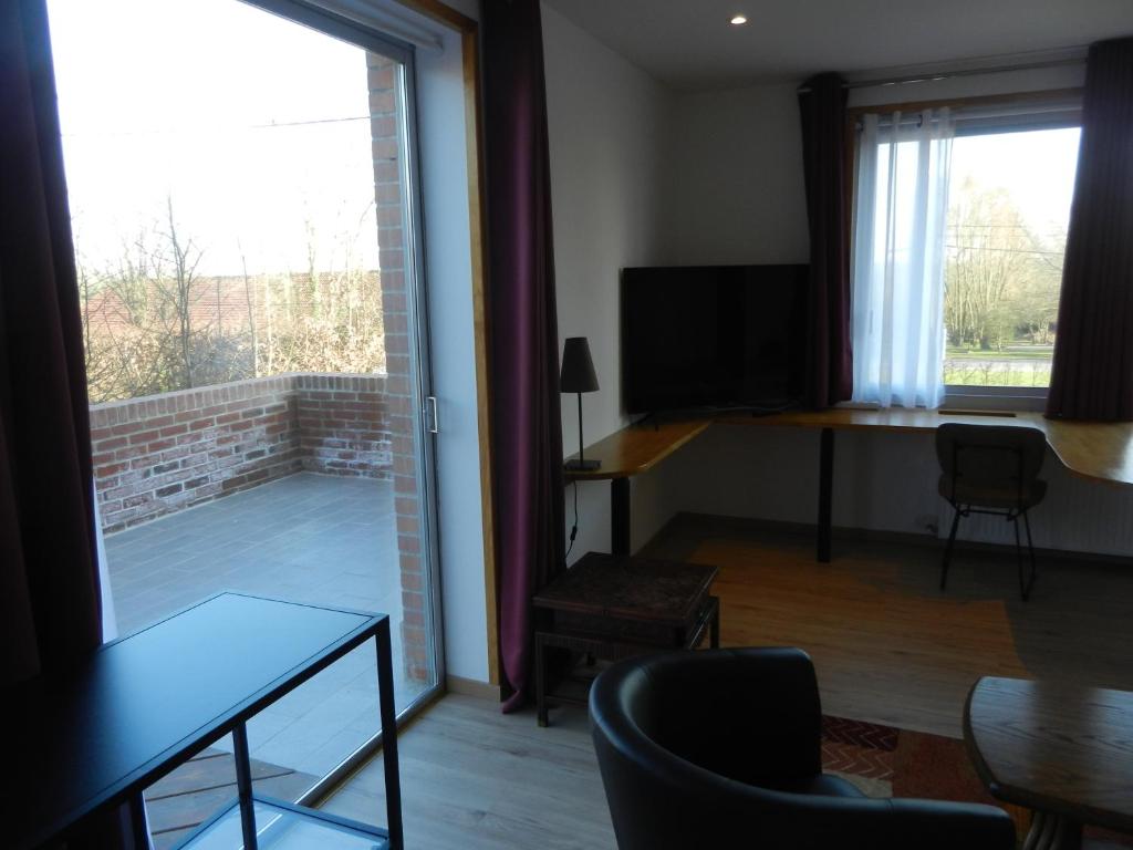 a living room with a large window and a television at Hôtel Les Charmilles de Mormal in Landrecies