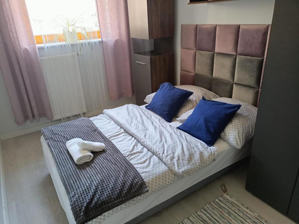 uma cama com almofadas azuis e toalhas em Apartament Polonia em Szczecin