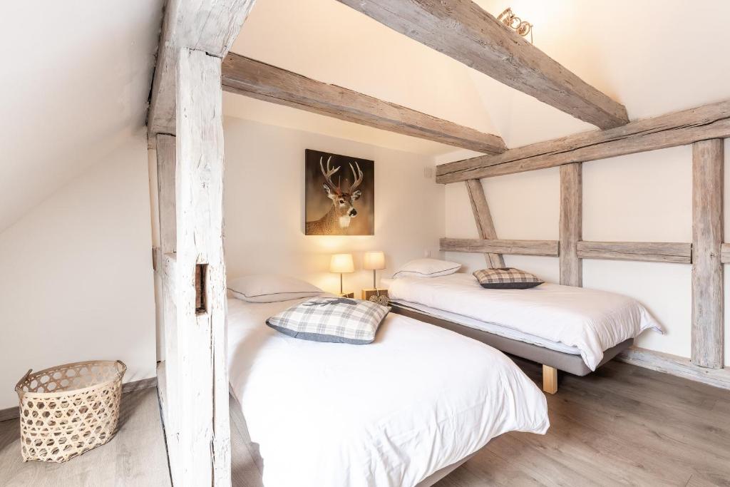 Habitación con 2 camas individuales y vigas de madera. en La maison d'Amélie, en Sommerau