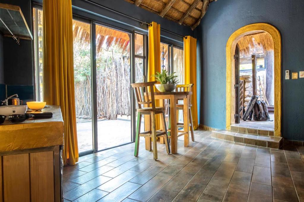 una cucina con tende gialle, tavolo e sedie di hippomoon lodge game reserve a Hoedspruit
