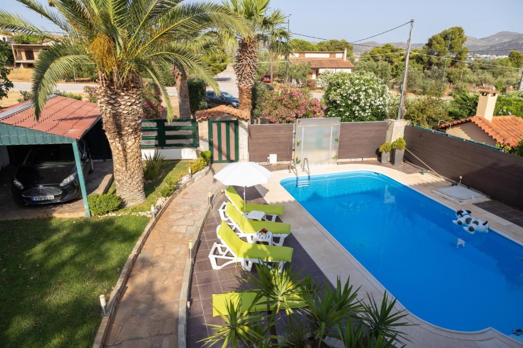 uma piscina com cadeiras e um guarda-sol ao lado de uma casa em Villa Rose em Anavissos