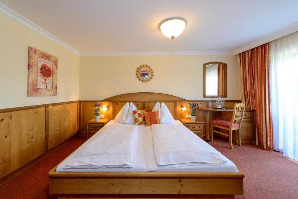 a bedroom with a large bed and a table at Landhotel Gersbach-Gut in Henndorf am Wallersee