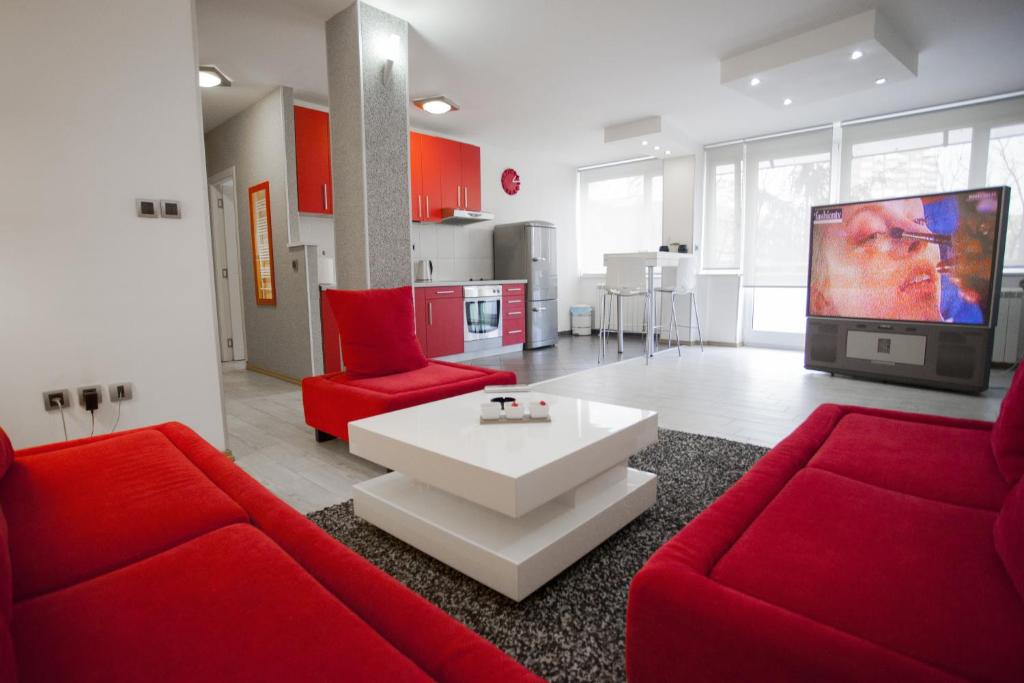 ein Wohnzimmer mit roten Möbeln und einem großen TV in der Unterkunft Apartment Red in Belgrad