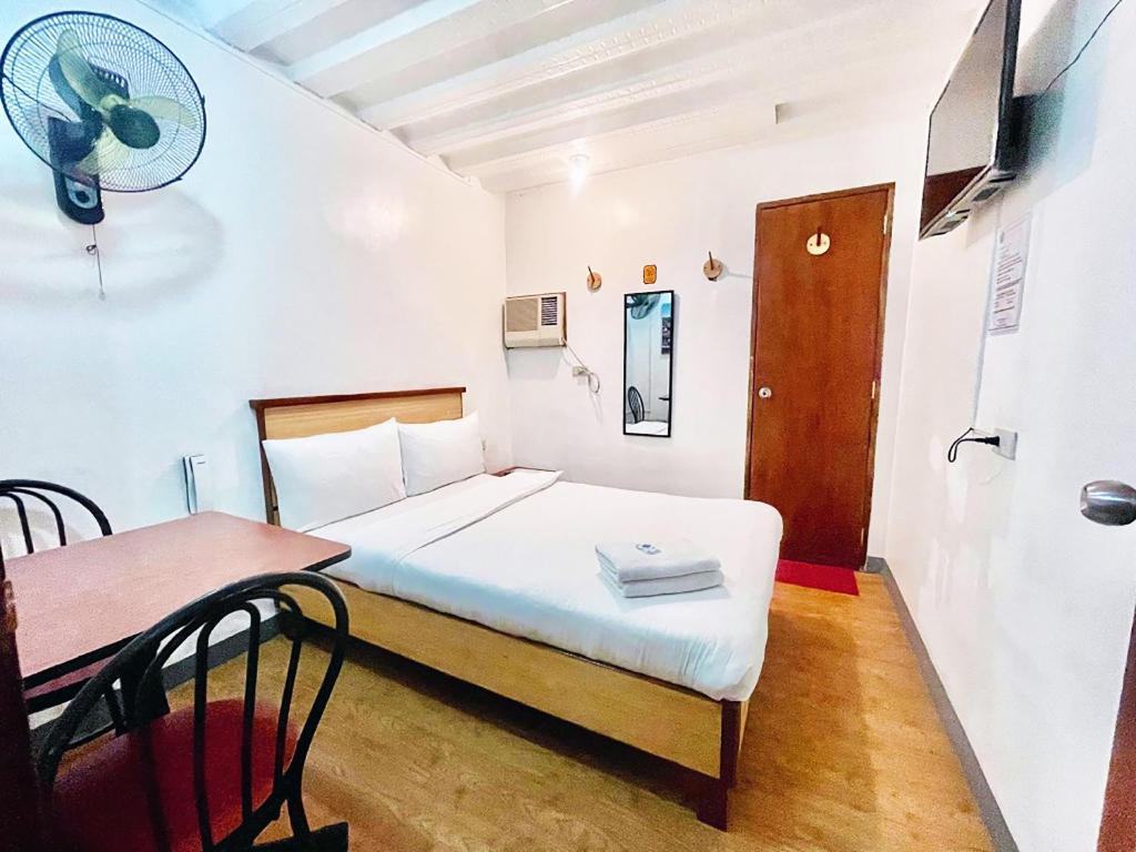um quarto com uma cama e uma mesa com uma ventoinha em Marion Hotel em Manila
